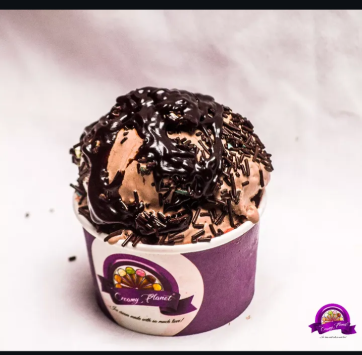 Chocolate ice cream scoop with syrup and sprinkles in a Creamy Planet cup