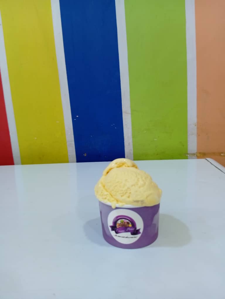 Pale yellow banana ice cream scoop in a purple Creamy Planet cup