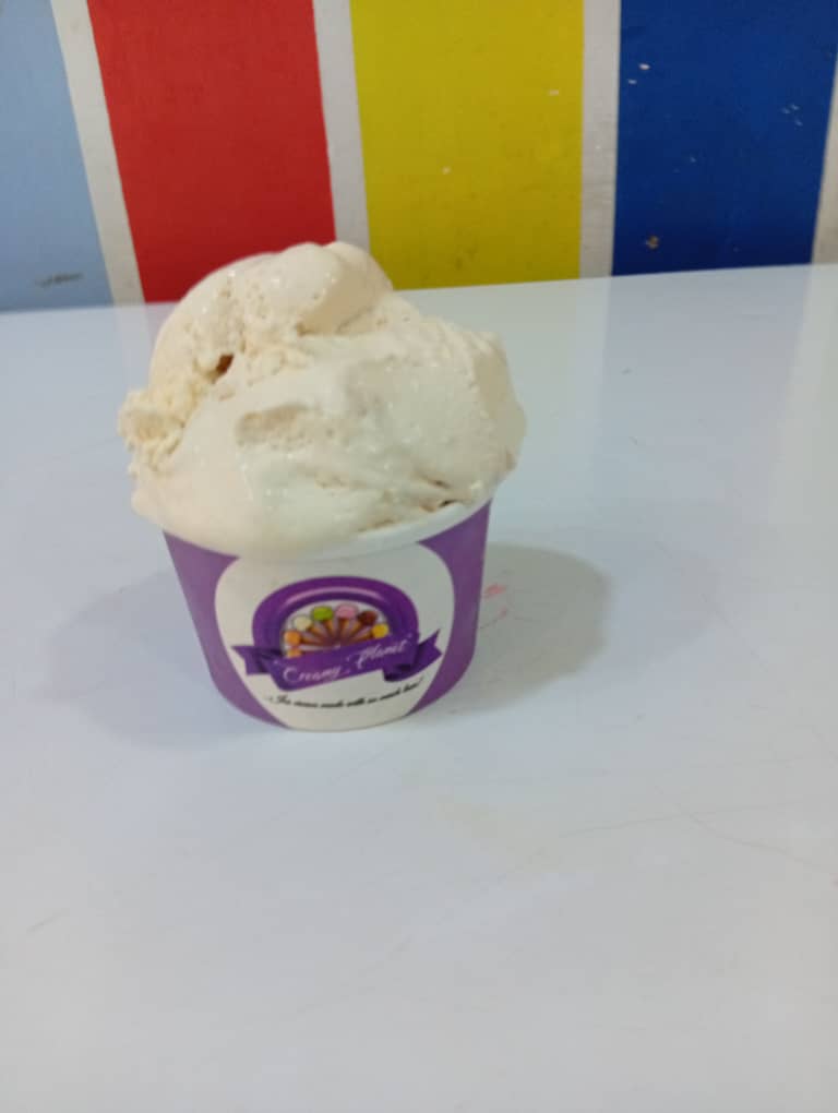 Cream-coloured vanilla ice cream scoop in a purple Creamy Planet cup
