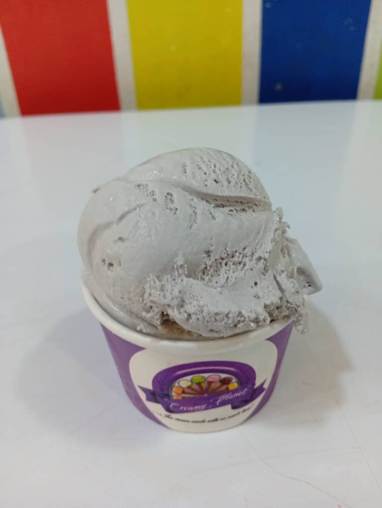 Grey-blue blue raspberry ice cream scoop in a purple Creamy Planet cup