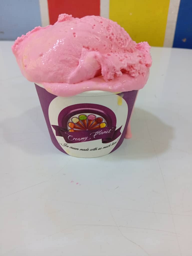 Pink strawberry ice cream scoop in a purple Creamy Planet cup