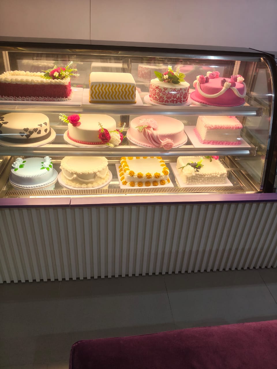 Display fridge of celebration cakes at Creamy Planet