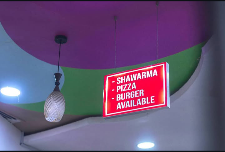 In-store sign showing shawarma, pizza and burgers available at Creamy Planet