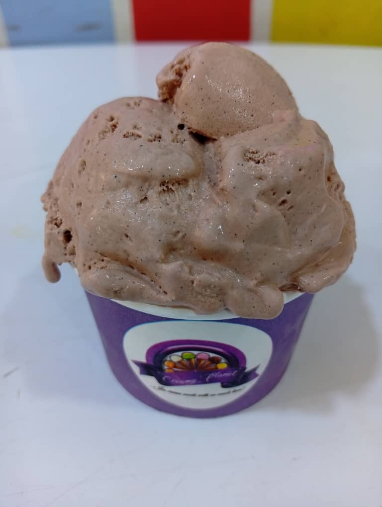 Brown chocolate ice cream scoops in a purple Creamy Planet cup